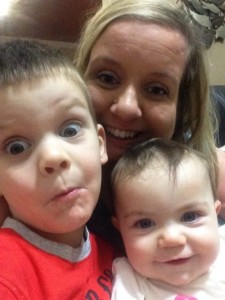 White woman center with a toddler boy and infant girl on either side. Close up headshot selfie of the three making silly faces.