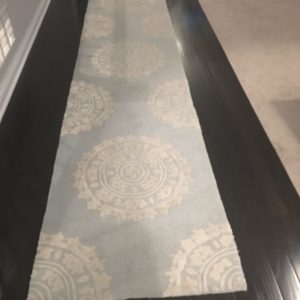 Photo of long narrow carpet on dark wood. This carpet separates room and location of toys.