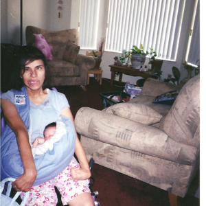 Photo shows mom in wheelchair holding baby using a baby carrier sling