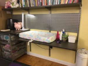 Photo shows baby changing table attached to book shelf and storage space