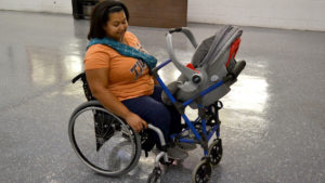 Photo of woman in wheelchair with stroller attached