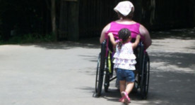 photo of little girl pushing woman in wheelchair