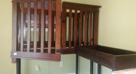Accessible wooden crib, door is cut down middle and open. Wooden changing table also shown