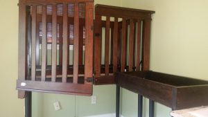 Accessible wooden crib, door is cut down middle and open. Wooden changing table also shown
