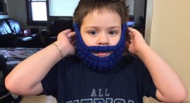 Young boy wearing knit hat with fake mustache and beard