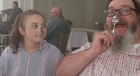 Father and daughter balancing spoons on their noses